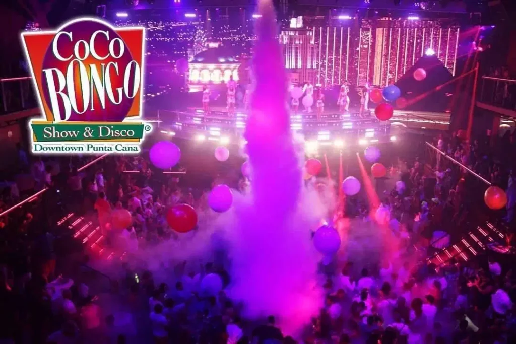 A vibrant nightclub scene at Coco Bongo Punta Cana shows a lively crowd dancing amid colorful lights, smoke, and giant balloons—a must-see for anyone seeking unforgettable Punta Cana tours. The Coco Bongo Show & Disco logo is in the top left corner.