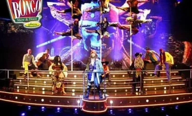 A vibrant stage at Coco Bongo Show & Disco features pirate-costumed performers and acrobats, set against dramatic lighting. This lively scene is a highlight of many Punta Cana tours, with the Coco Bongo logo in the top left.