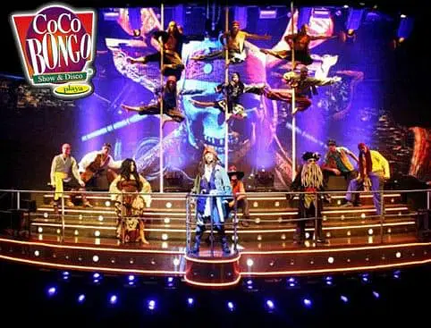 A vibrant stage at Coco Bongo Show & Disco features pirate-costumed performers and acrobats, set against dramatic lighting. This lively scene is a highlight of many Punta Cana tours, with the Coco Bongo logo in the top left.