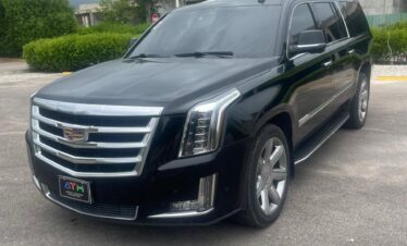 A black Cadillac Escalade SUV, perfect for VIP transfer, is parked outdoors with tinted windows, chrome accents, large rims, and a bold Cadillac emblem. Trees, a concrete building, and a cloudy sky frame the Punta Cana setting.