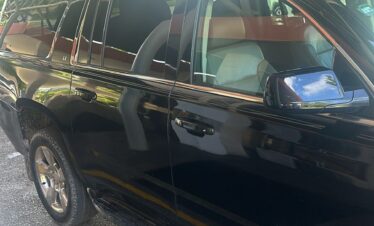 A sleek black car awaits in the parking lot, ready for a VIP transfer in Punta Cana.