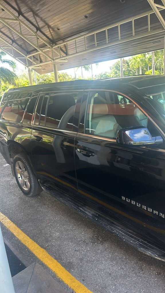 A sleek black car awaits in the parking lot, ready for a VIP transfer in Punta Cana.